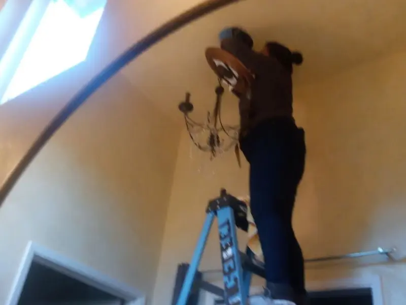 Electrician installing a chandelier in a La Verne residence